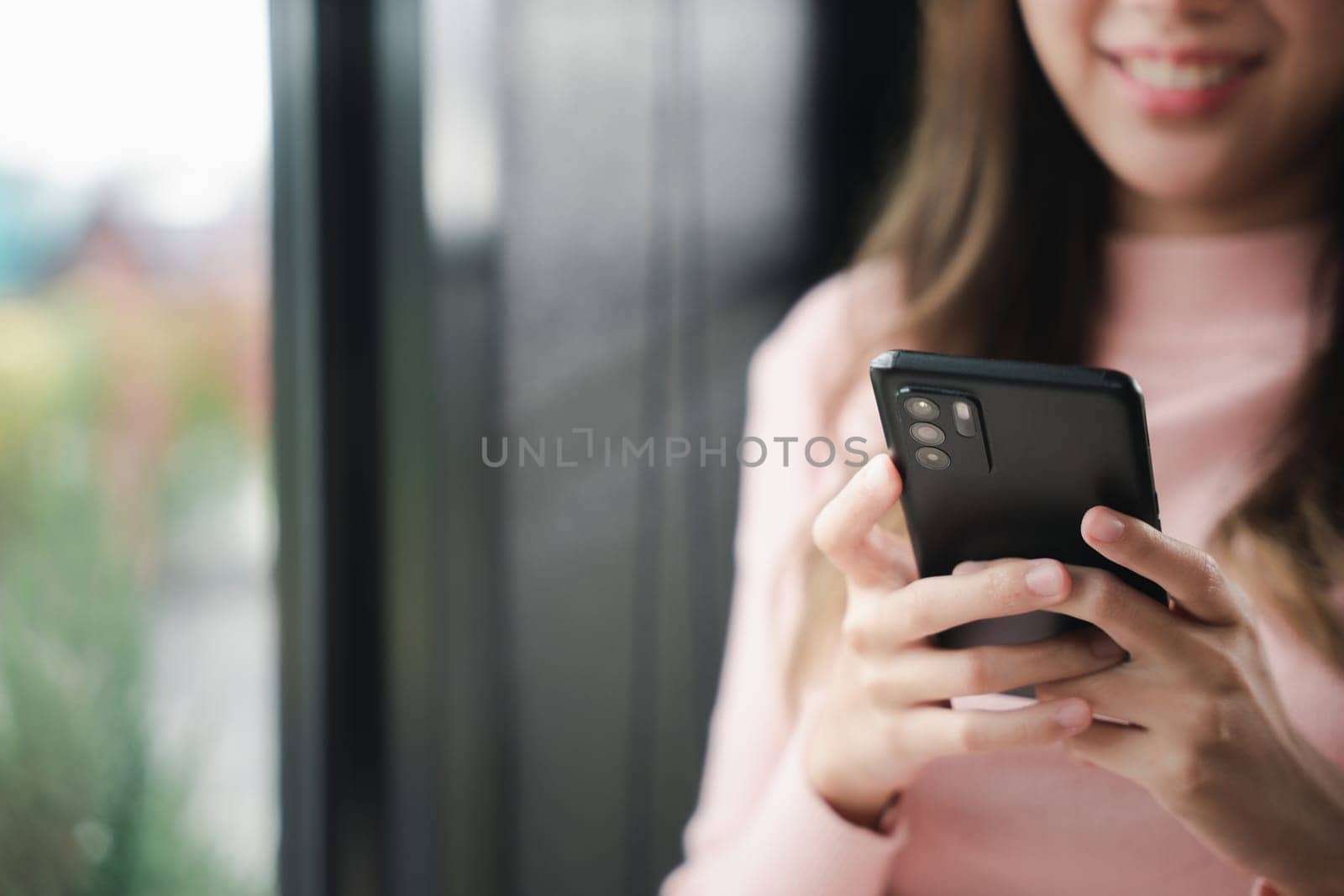 Happy beautiful female typing text message on smart phone device and enjoyment lifestyle with social networking media, Asian young woman using mobile phone at cafe coffee shop to shopping online