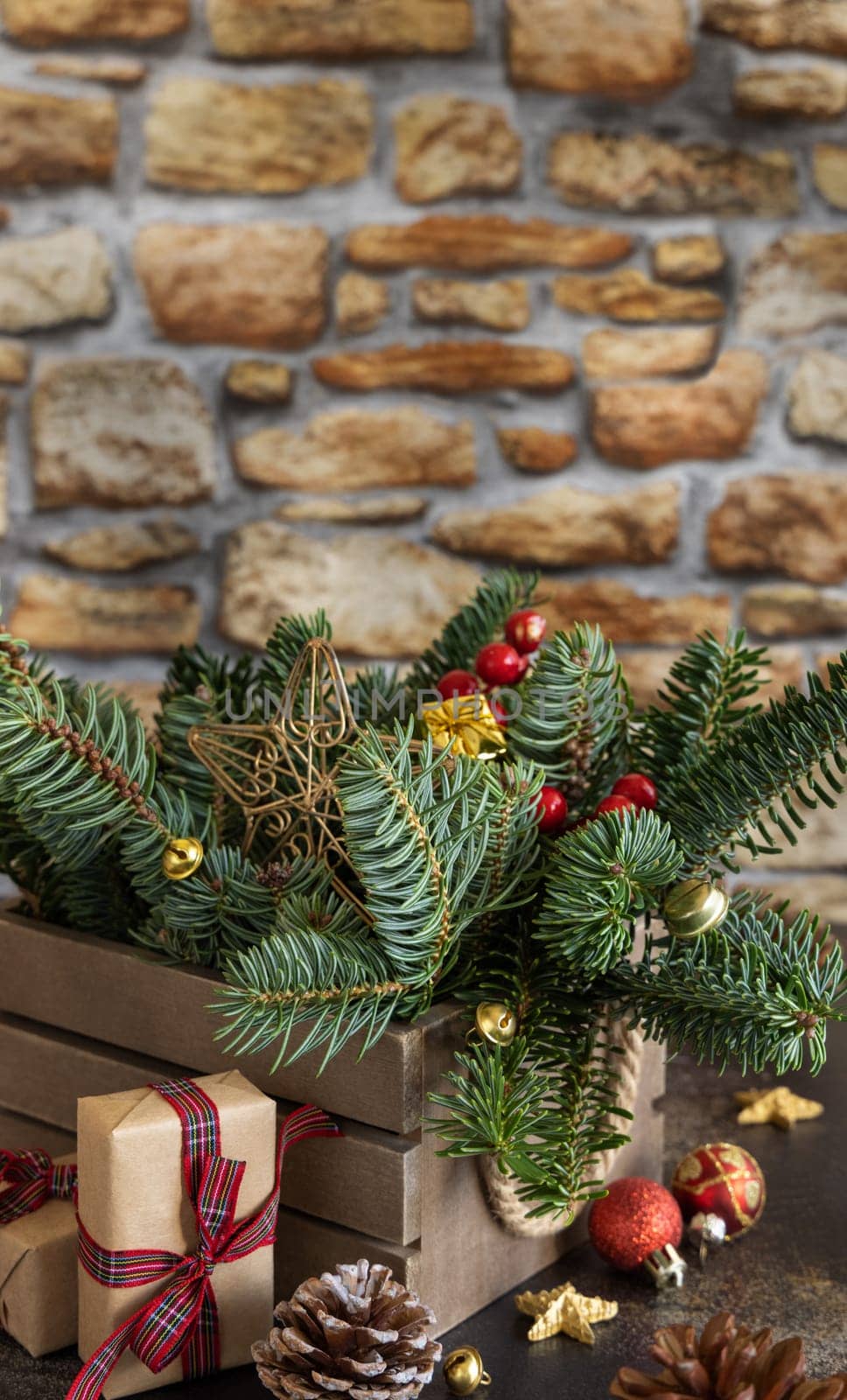 Wrapped gift boxes near Christmas decorations, pine cones and green fir branches close up with copy space, close up with brick wall. Christmas or New Year Holiday atmosphere composition