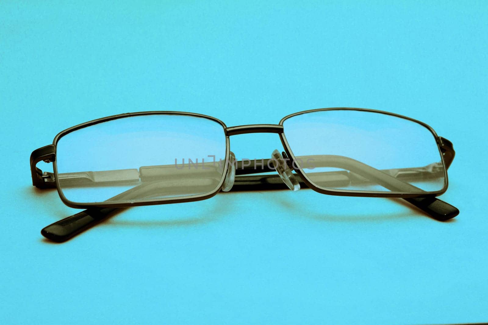 Glasses in a black frame on a blue background with copy space. World Day of Sight.