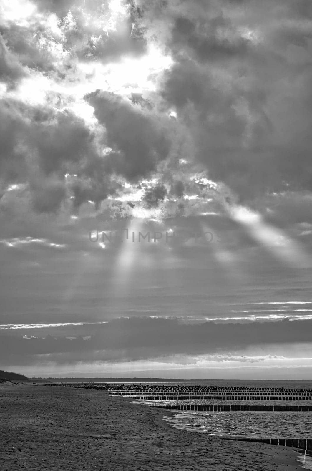 in spring a view over the beach in Zingst on the Baltic Sea. Walk by the sea in black and white. Moving clouds in the sky