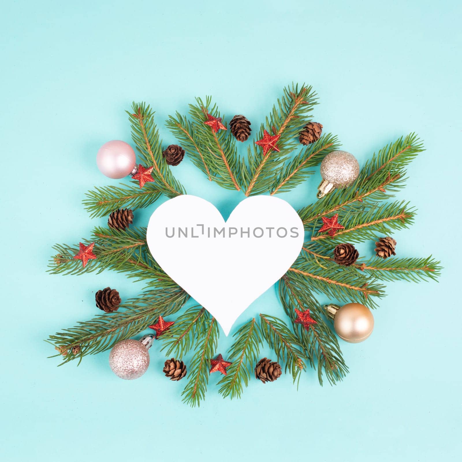 Christmas holiday background in heart shape, frame with fir branches, baubles and pine cones, winter season greeting card