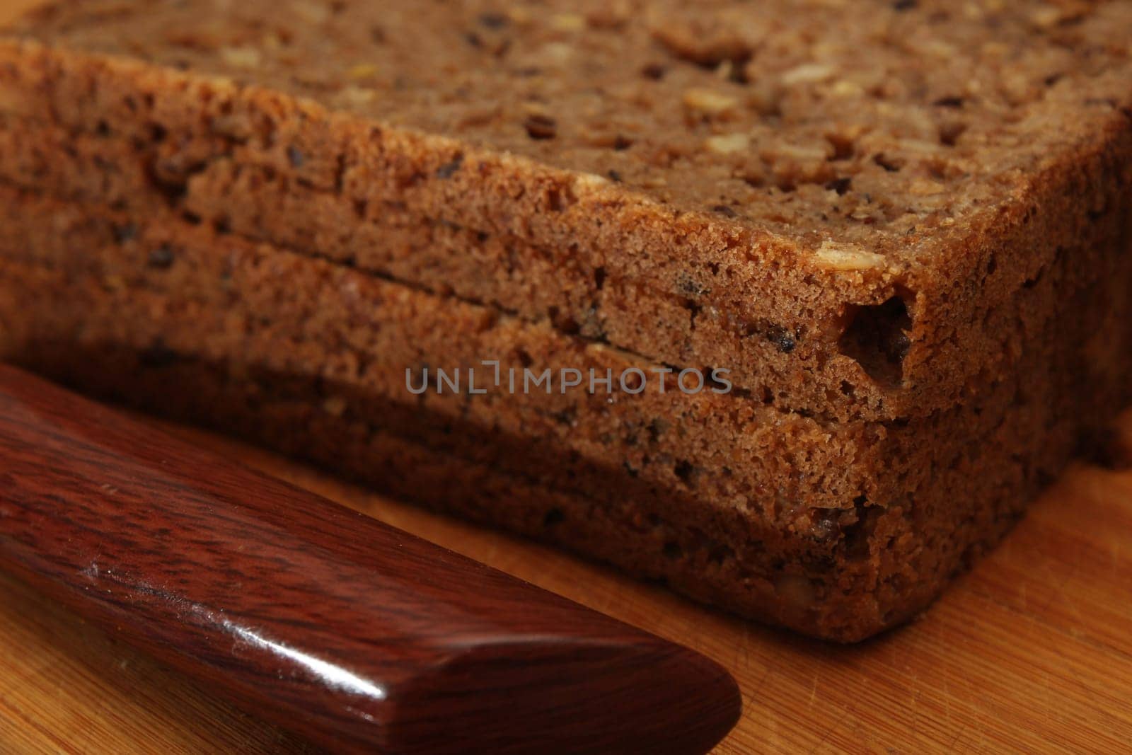Sliced whole grain bread with a knife close-up on a wooden board. Defocus. Healthy food concept.