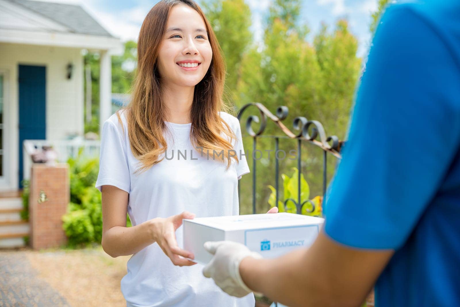 Sick Asian young woman receive medication first aid pharmacy box from hospital delivery service, delivery man give medicine drug to patient female at home, healthcare medicine online concept
