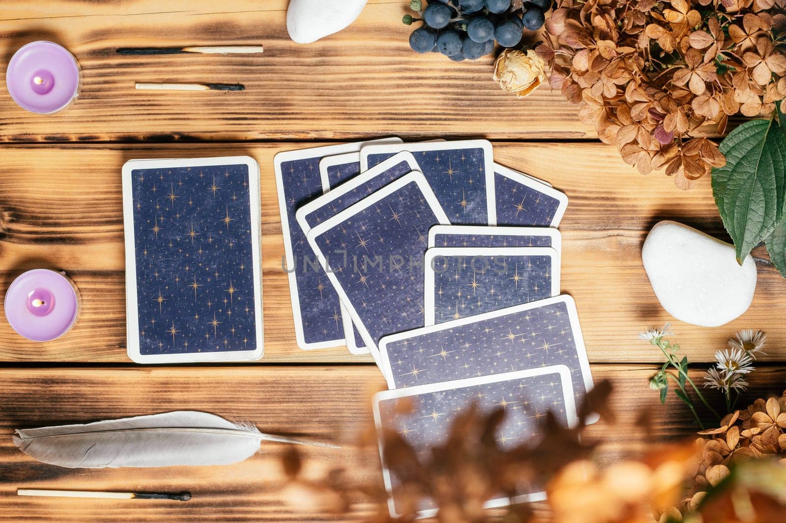 Tarot cards spread face down on wooden surface with candles, stones, autumn plants and accessories. Top view. Minsk, Belarus, 11.10.2021