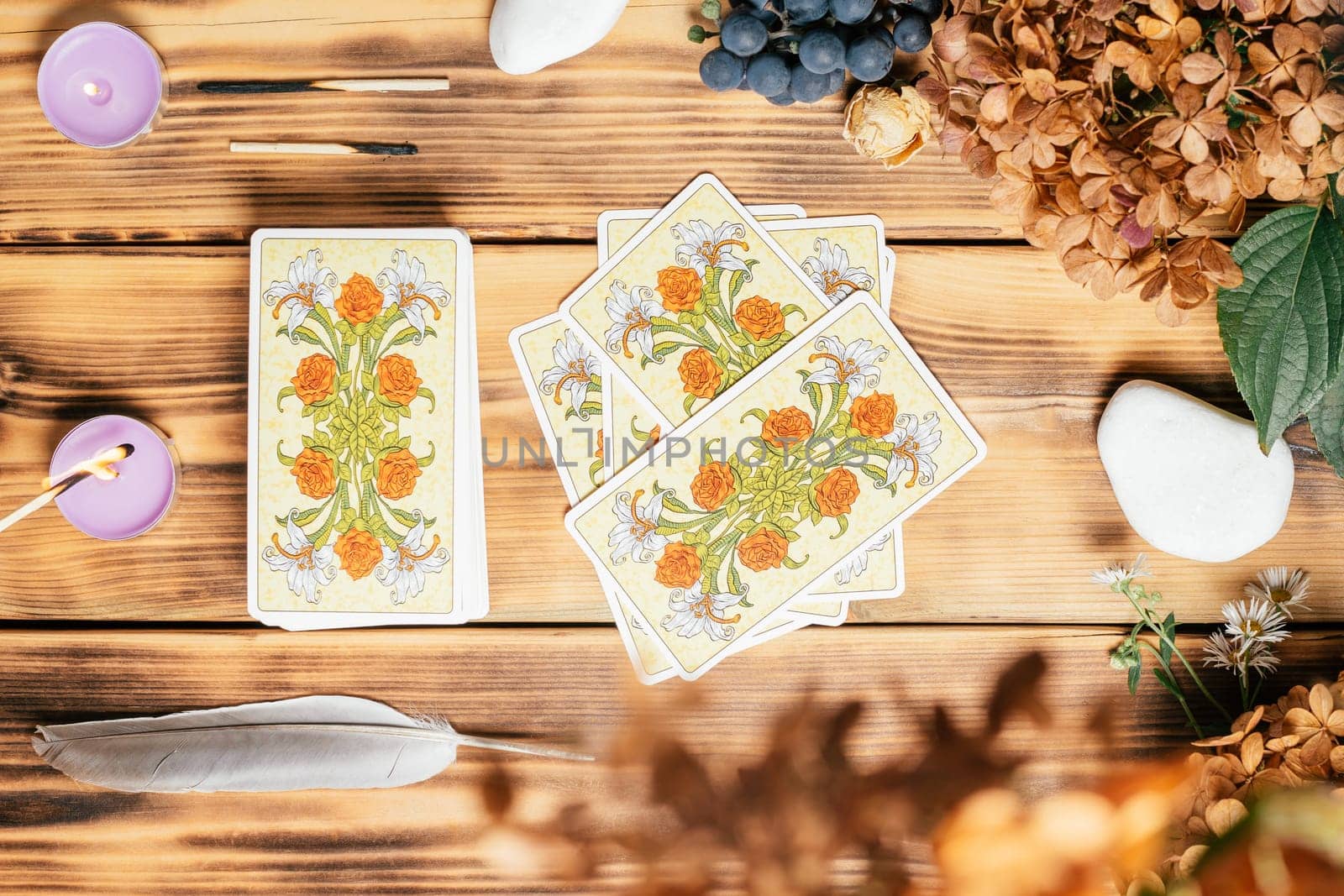 Tarot cards spread face down on wooden surface with candles, stones, autumn plants and accessories. Top view. Minsk, Belarus, 11.10.2021