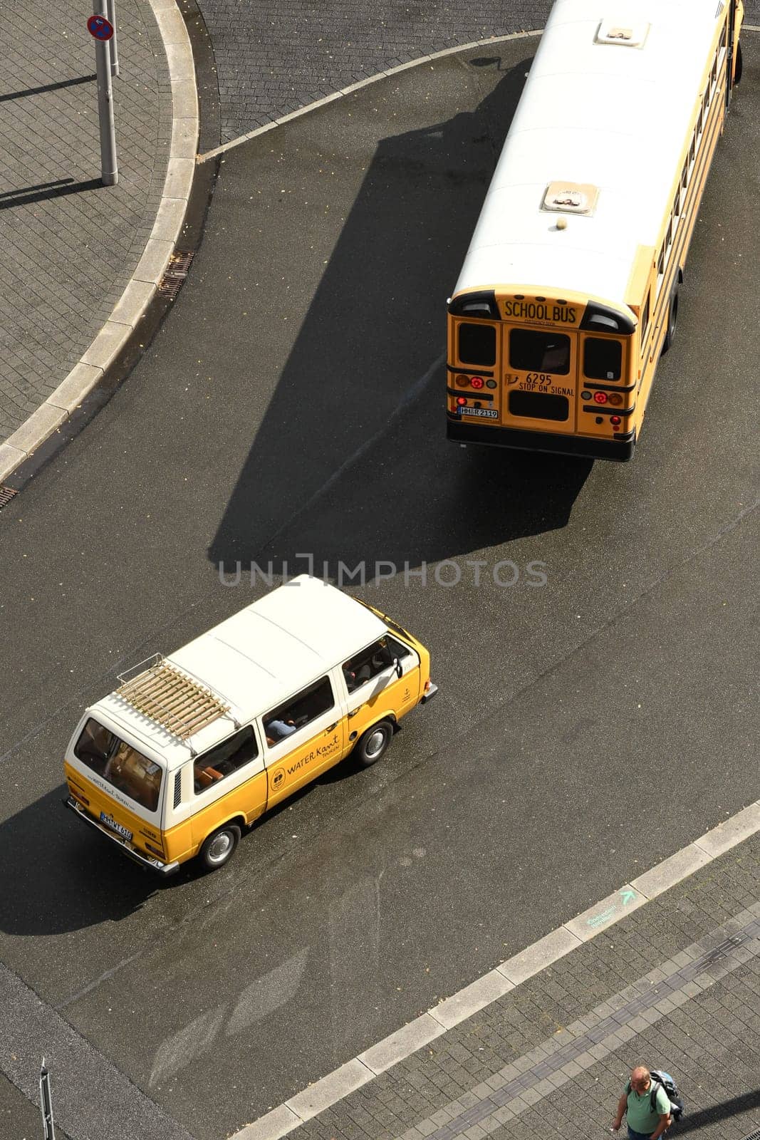 Aerial view of an American school bus with a white and yellow small bus coming from behind