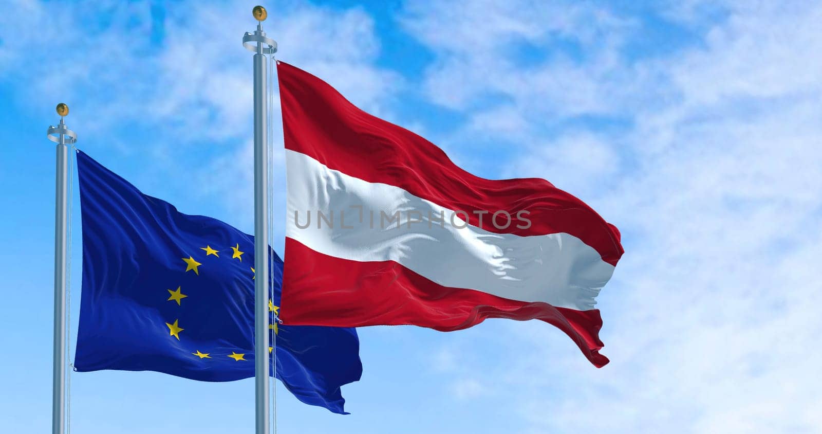 Detail of the national flag of Austria waving in the wind with blurred european union flag in the background on a clear day. Democracy and politics. European country. Selective focus.