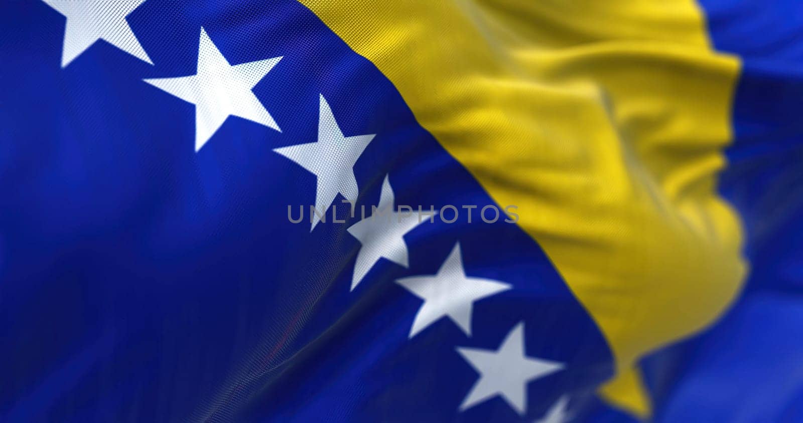 Close-up view of the bosnian national flag waving in the wind. Bosnia and Herzegovina is a country at the crossroads of south and southeast Europe. Fabric textured background. Selective focus