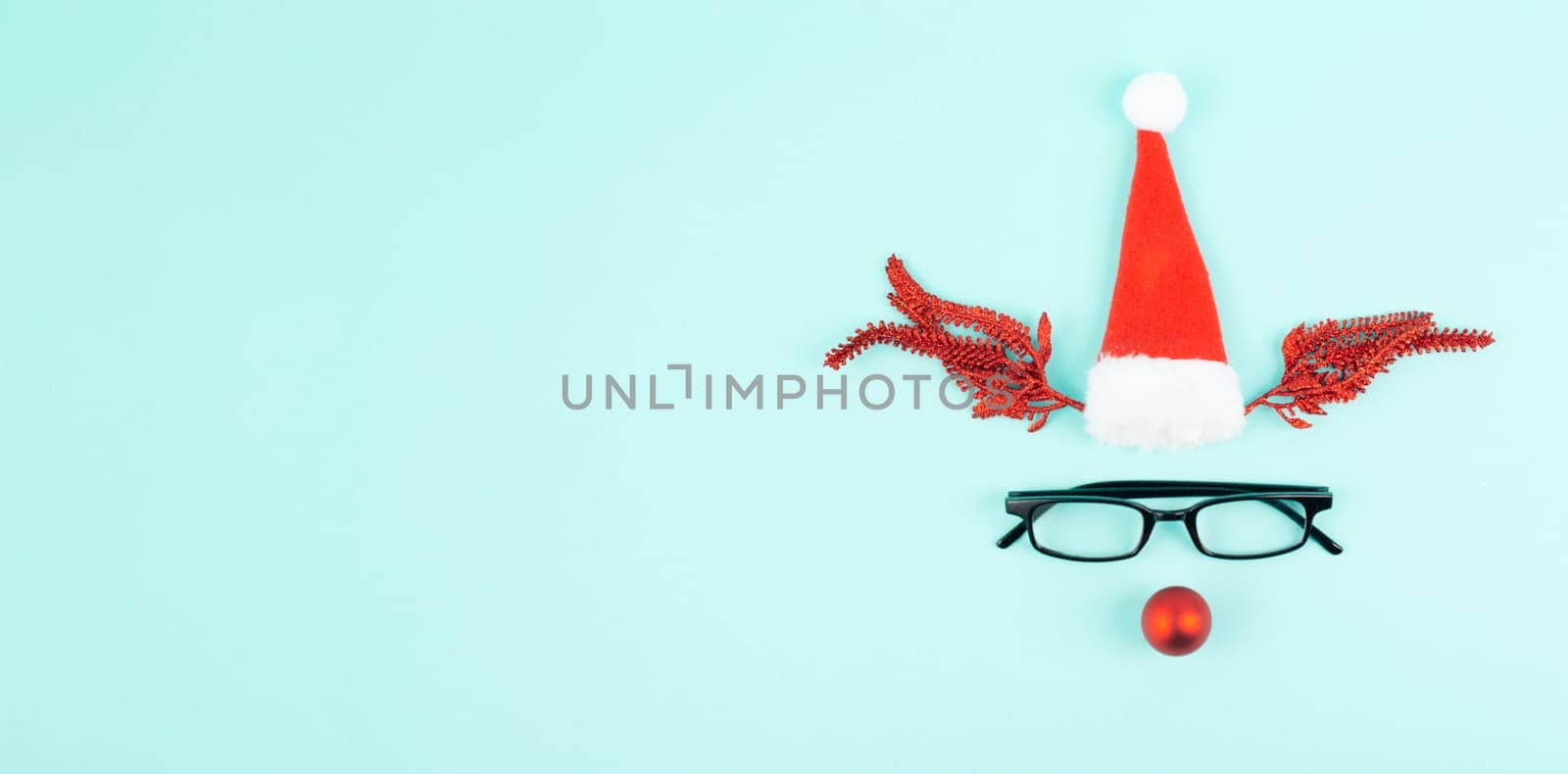 Reindeer with a red bauble nose, antlers, a santa claus hat and eyeglasses, merry christmas greeting card