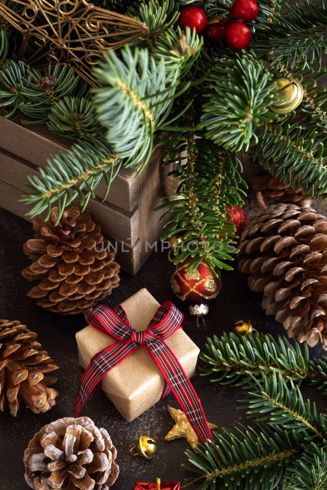 Wrapped gift boxes between Christmas decorations, pine cones and green fir branches close up. Christmas or New Year Holiday atmosphere flat lay