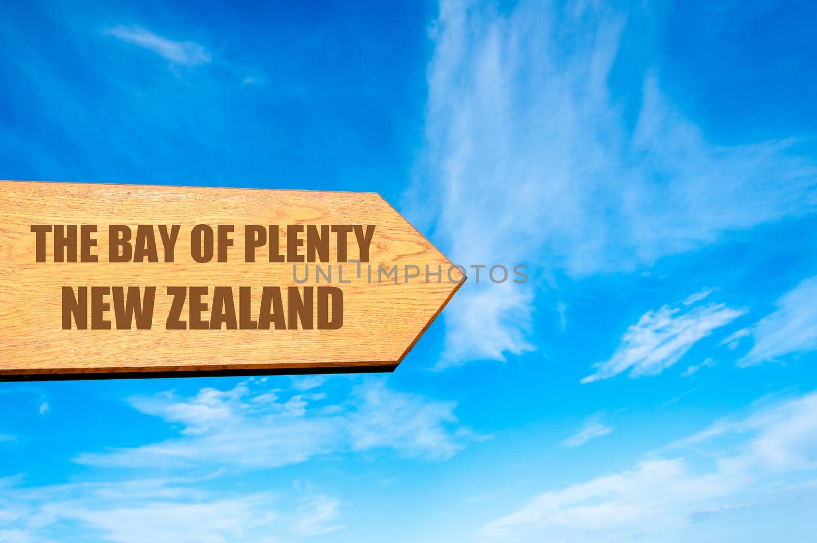 Wooden arrow sign pointing destination The Bay Of Plenty, NEW ZEALAND against clear blue sky with copy space available. Travel destination concept  image