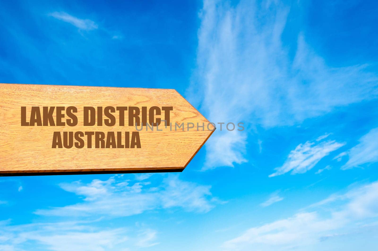 Wooden arrow sign pointing destination LAKES DISTRICT, AUSTRALIA  against clear blue sky with copy space available. Travel destination concept  image