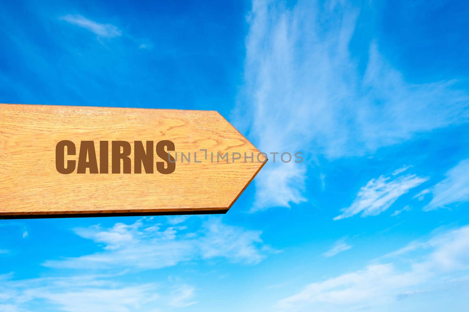 Wooden arrow sign pointing destination CAIRNS, , AUSTRALIA  against clear blue sky with copy space available. Travel destination concept  image