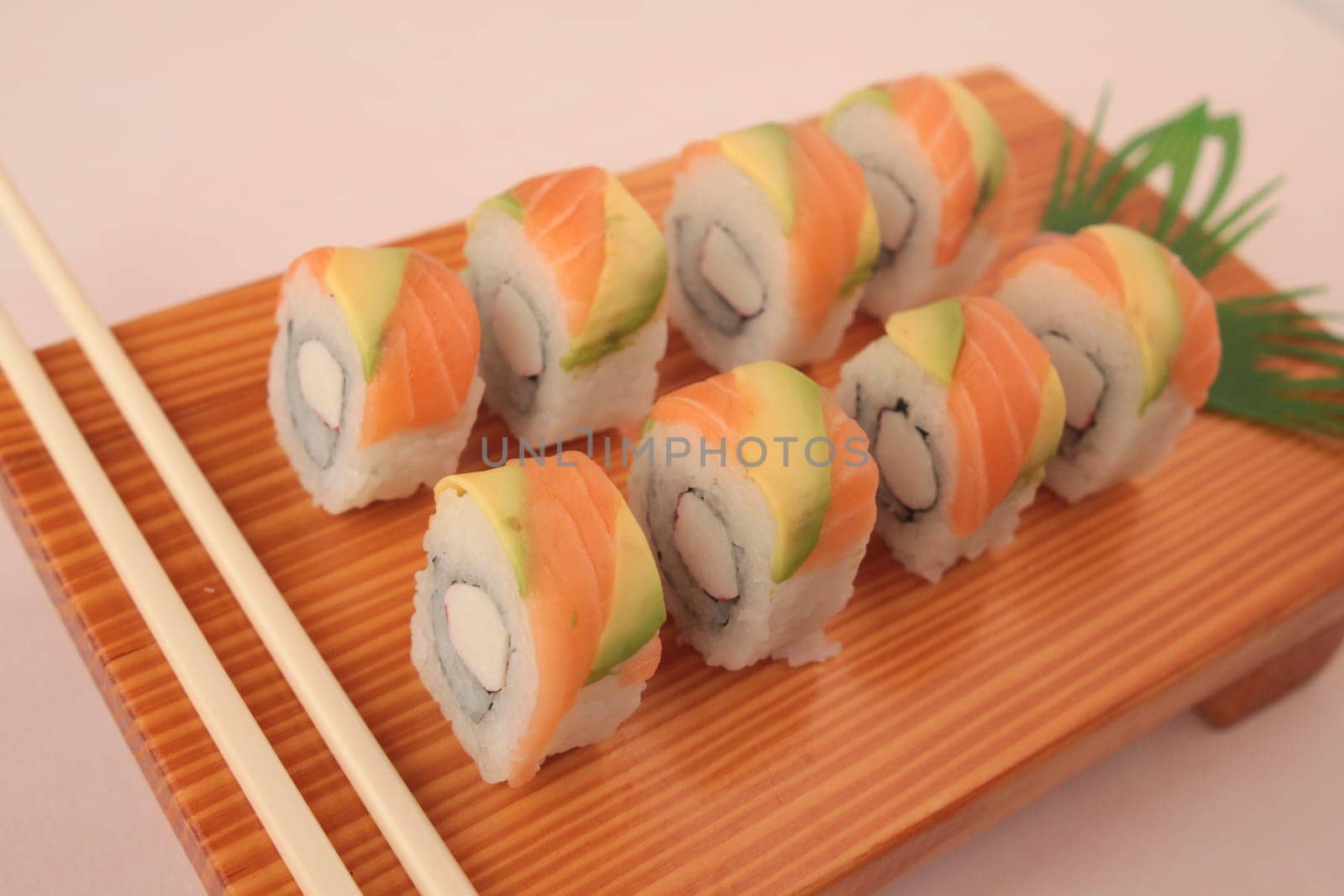 sushi with salmon and avocado on wooden plate