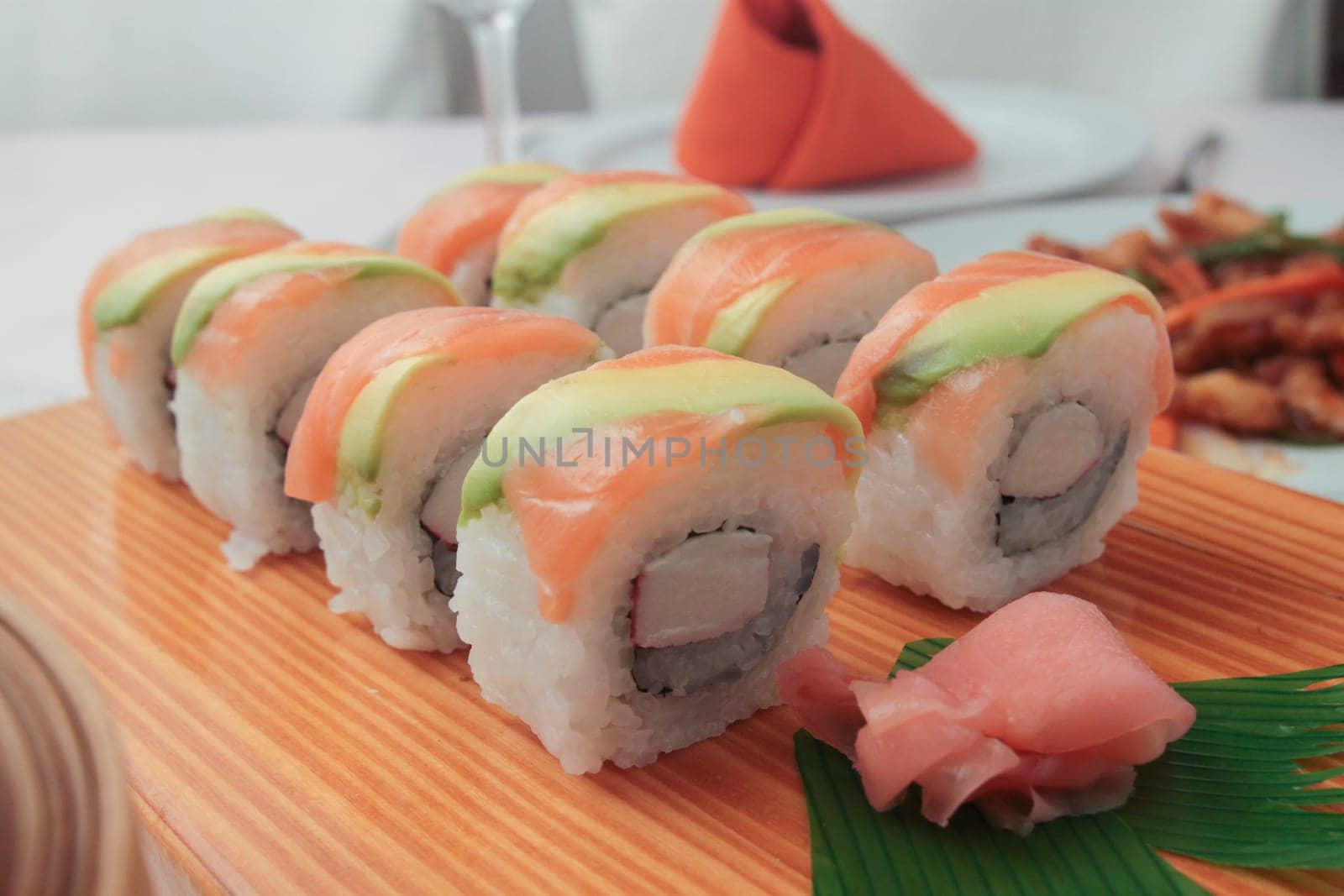 sushi with salmon and avocado on wooden plate