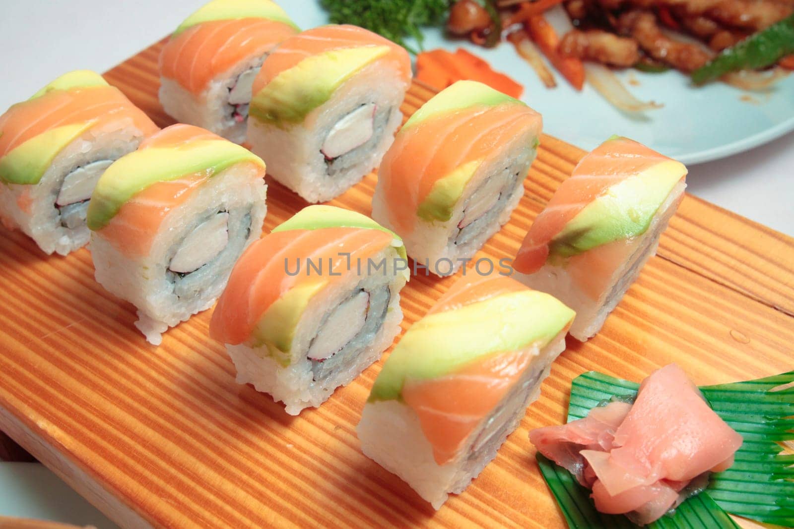 sushi with salmon and avocado on wooden plate