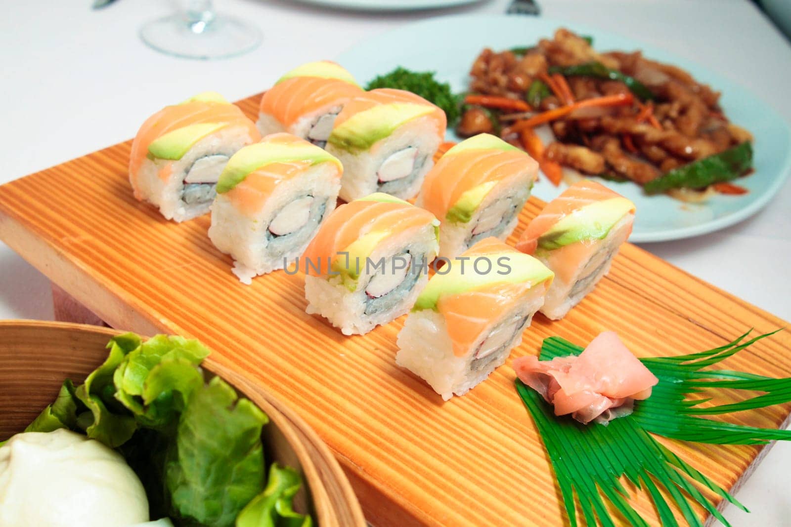 sushi with salmon and avocado on wooden plate