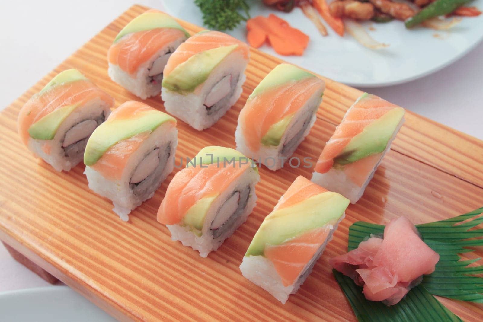sushi with salmon and avocado on wooden plate