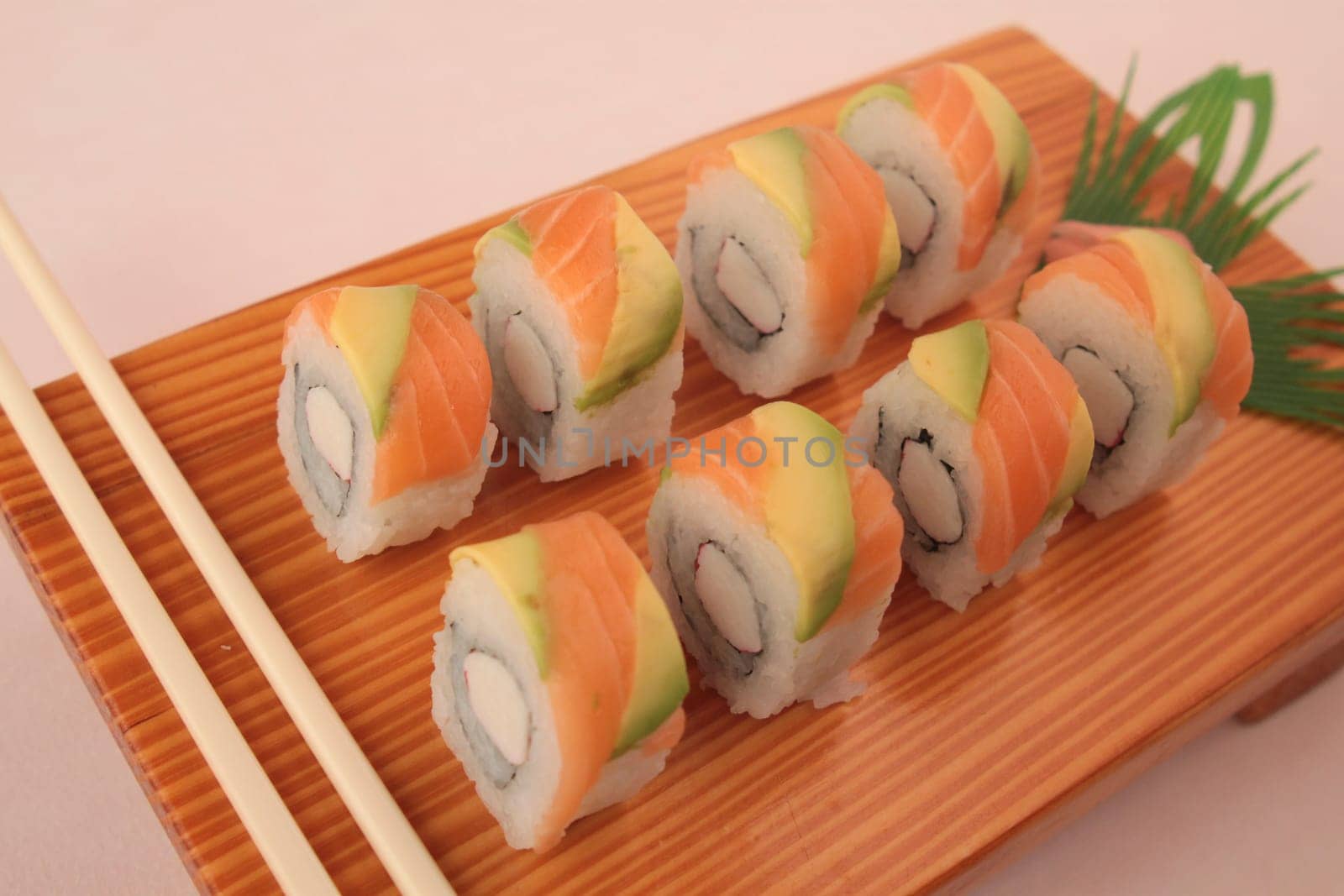sushi with salmon and avocado on wooden plate