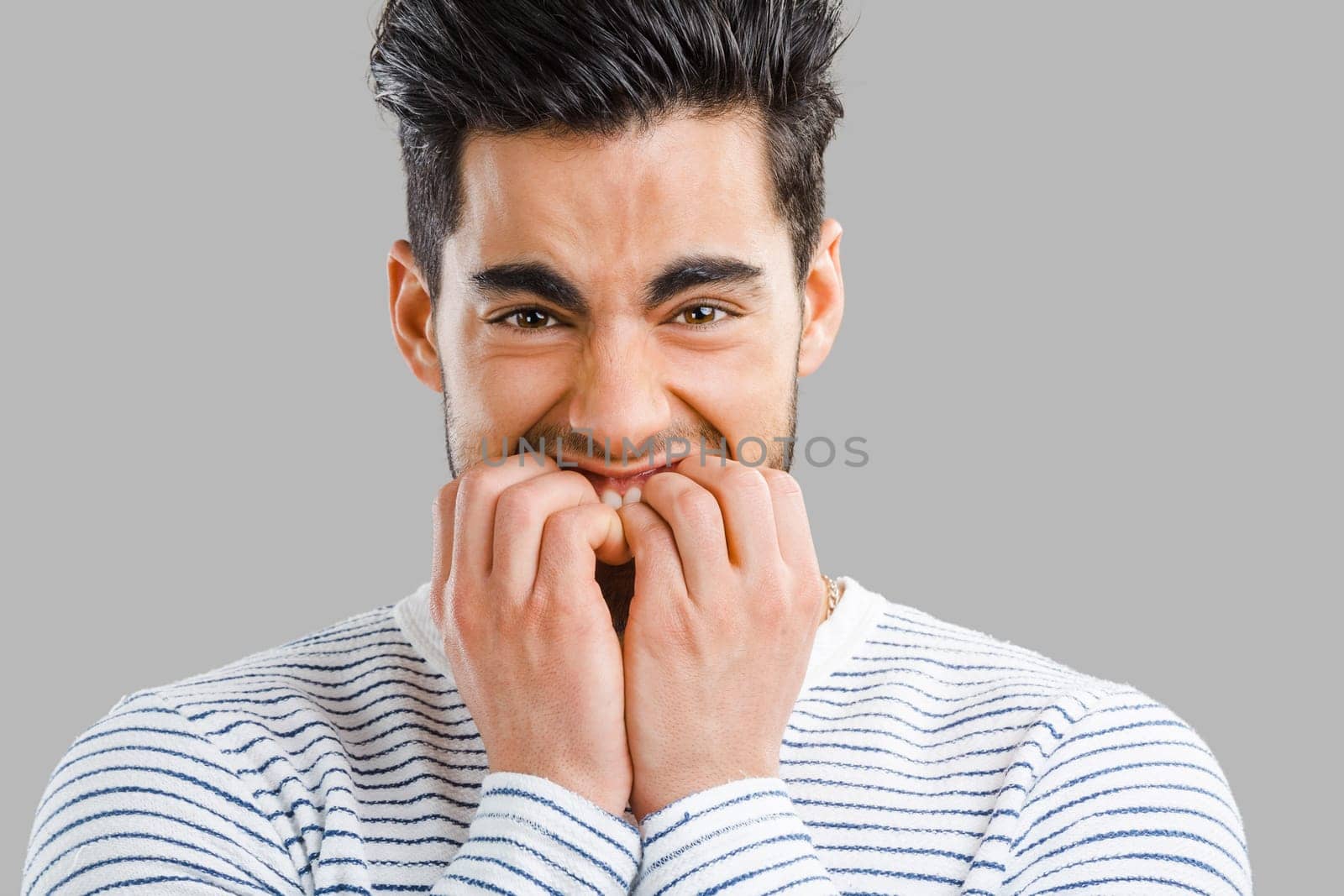 Close-up portrait of a worried young man biting nails