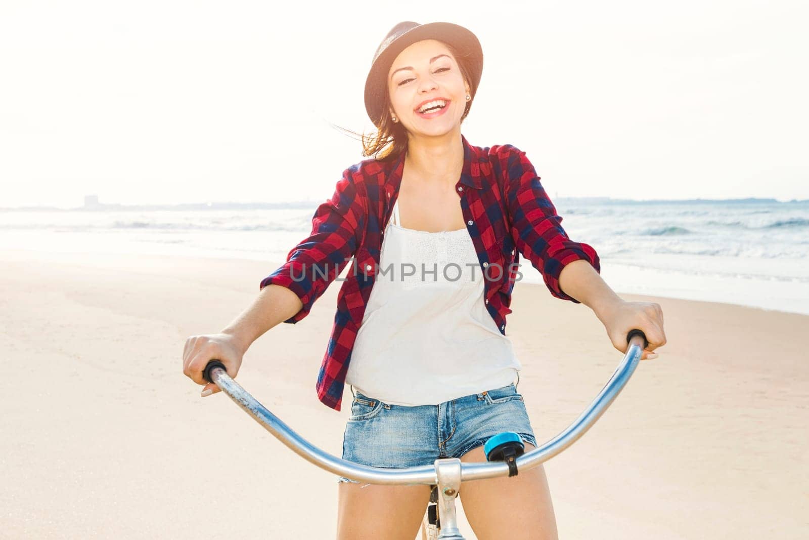 An attractive young woman riding her bicycle on the beach