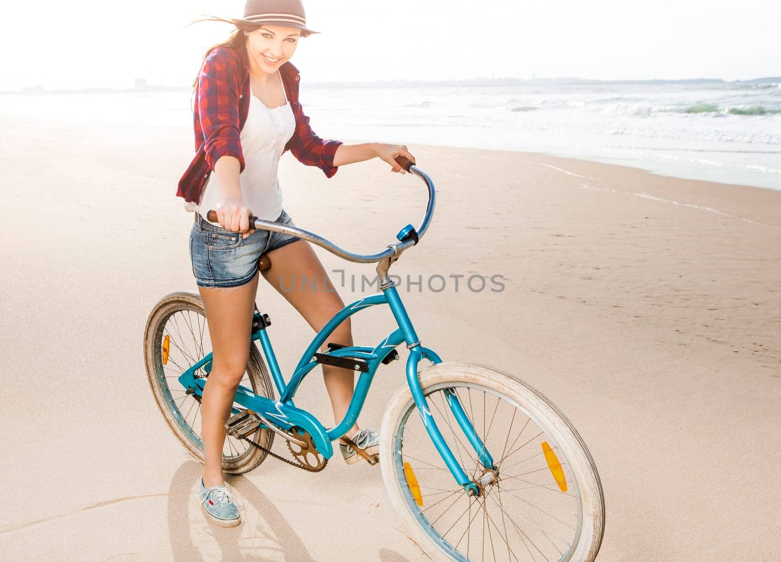 An attractive young woman riding her bicycle on the beach