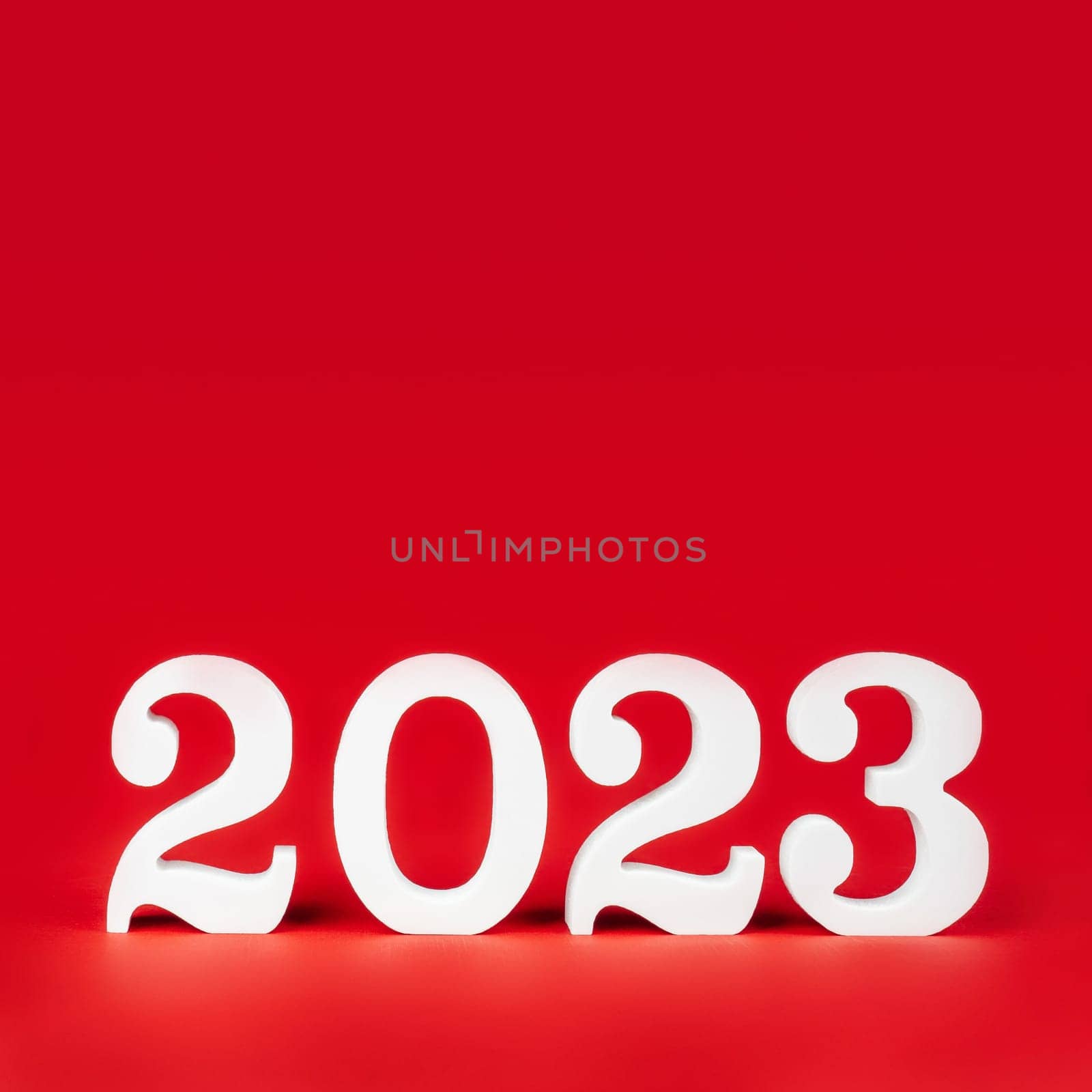 Happy New Year 2023. Bright red square banner with white wooden numbers 2023 stand at bottom. Merry Christmas. Copy space. Place for text