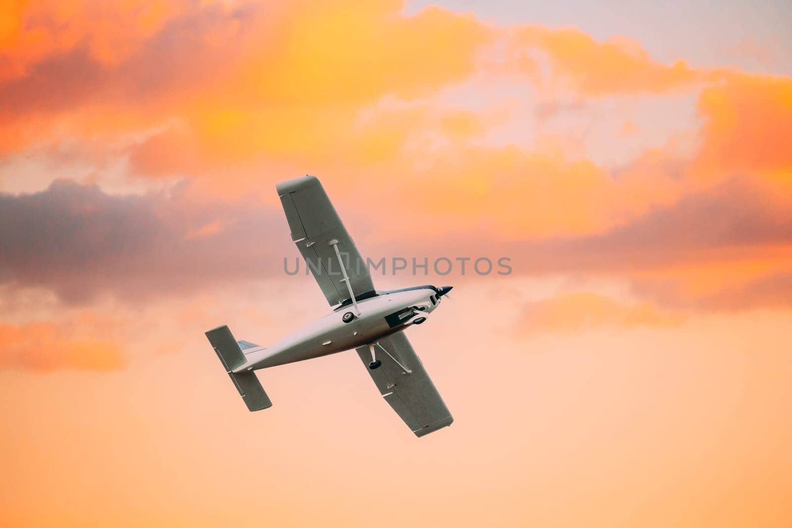 Light aircraft Flying In Sunny Sunset Sky.
