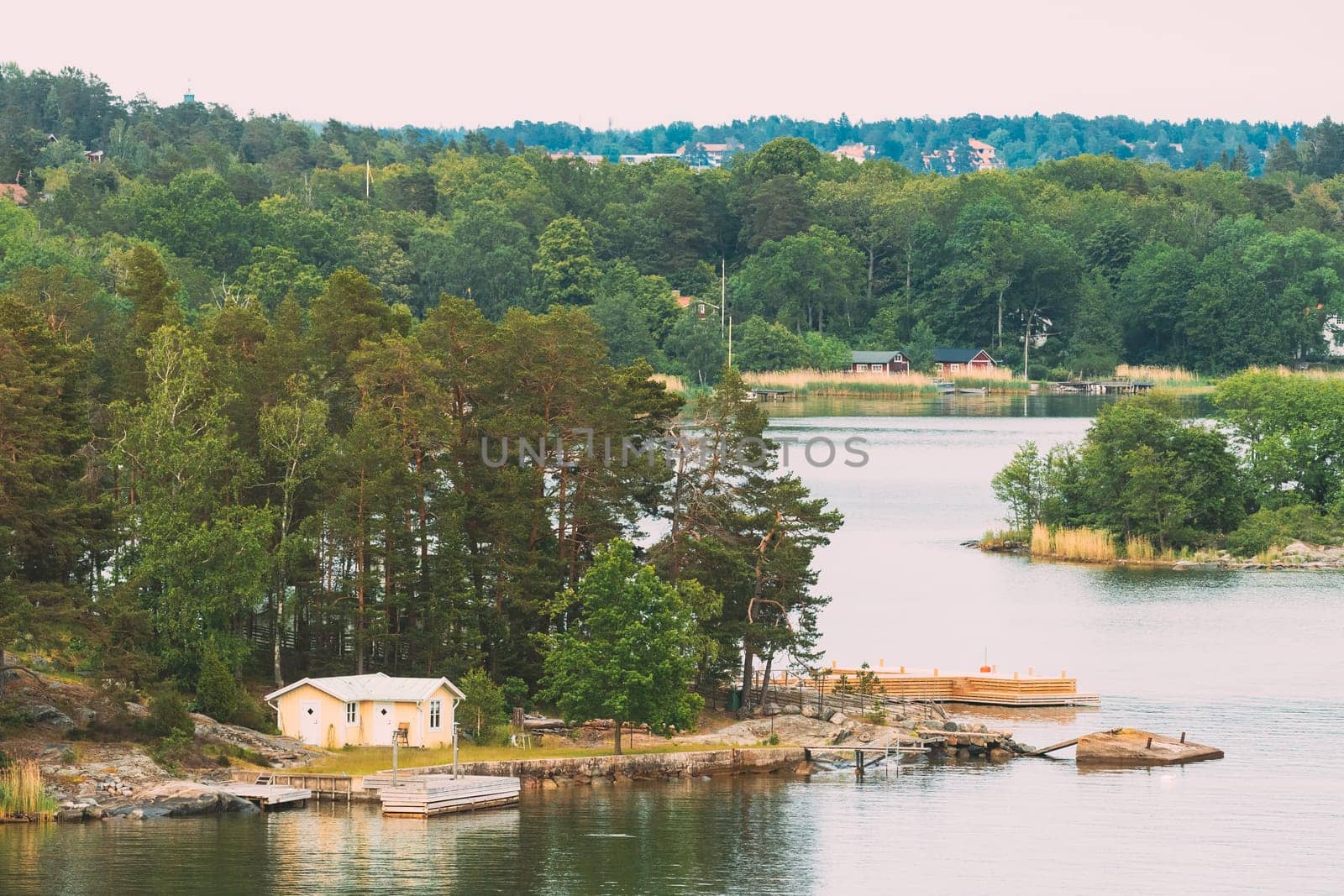 Sweden. Beautiful Swedish Wooden Log Cabins Houses On Rocky Island Coast In Summer Day. Lake Or River Landscape.