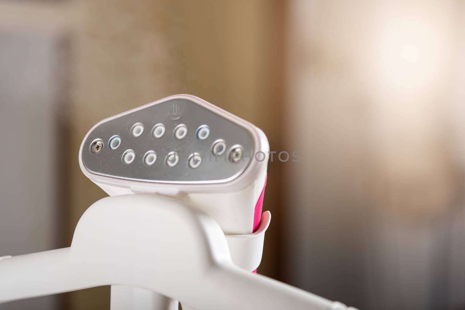 Close up of electric hand steam generator while it's hot on the ironing board place for clothes at house, Household & home equipment for housework, concept of linen care