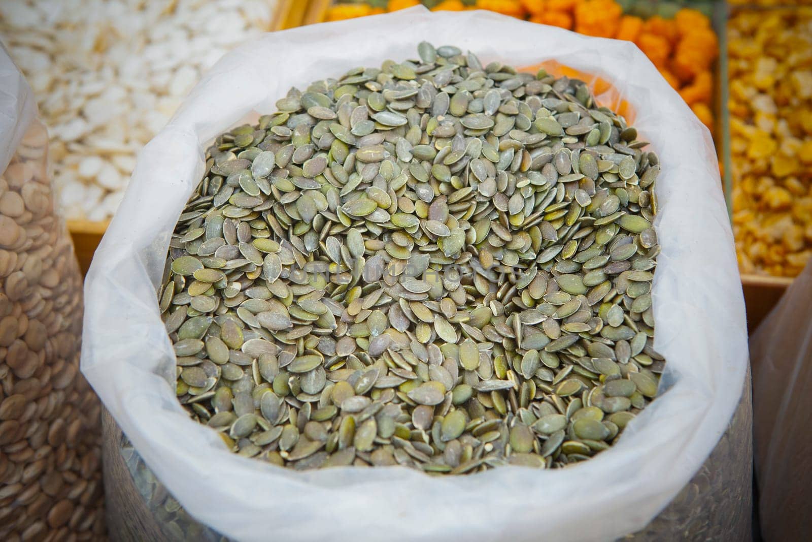 Whole dried pumpkin seeds on rolled up sack. Displayed at street market stall