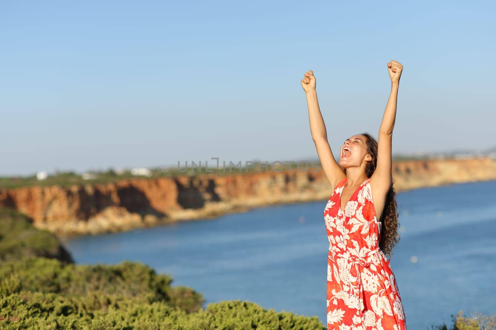 Excited tourist on the beach raising arms celebrating summer vacation