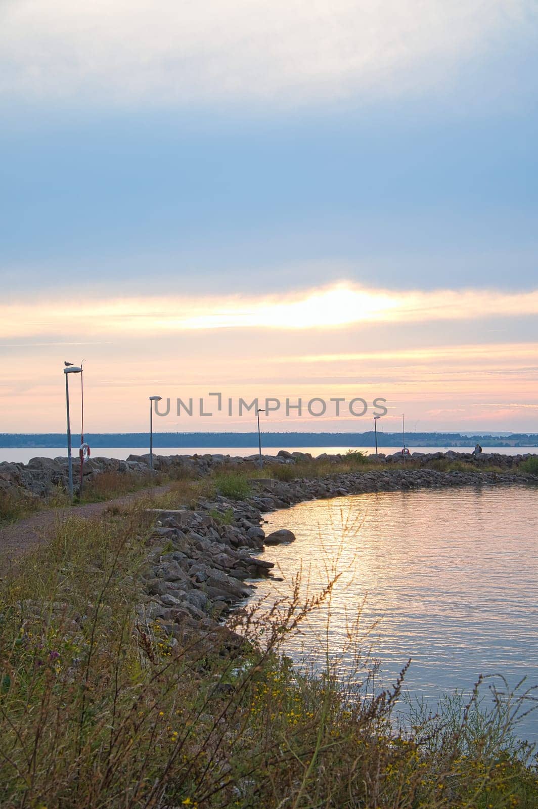 Sunset in Sweden at the harbor of lake Vaettern. Lighthouse in the background at dusk. Landscape shot in Scandinavia.