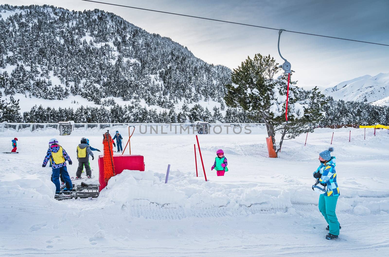 Ski trainers teaching group of young kids how to ski in ski school Mother watching her daughter on ski Winter holidays in Andorra Pyrenees Mountains