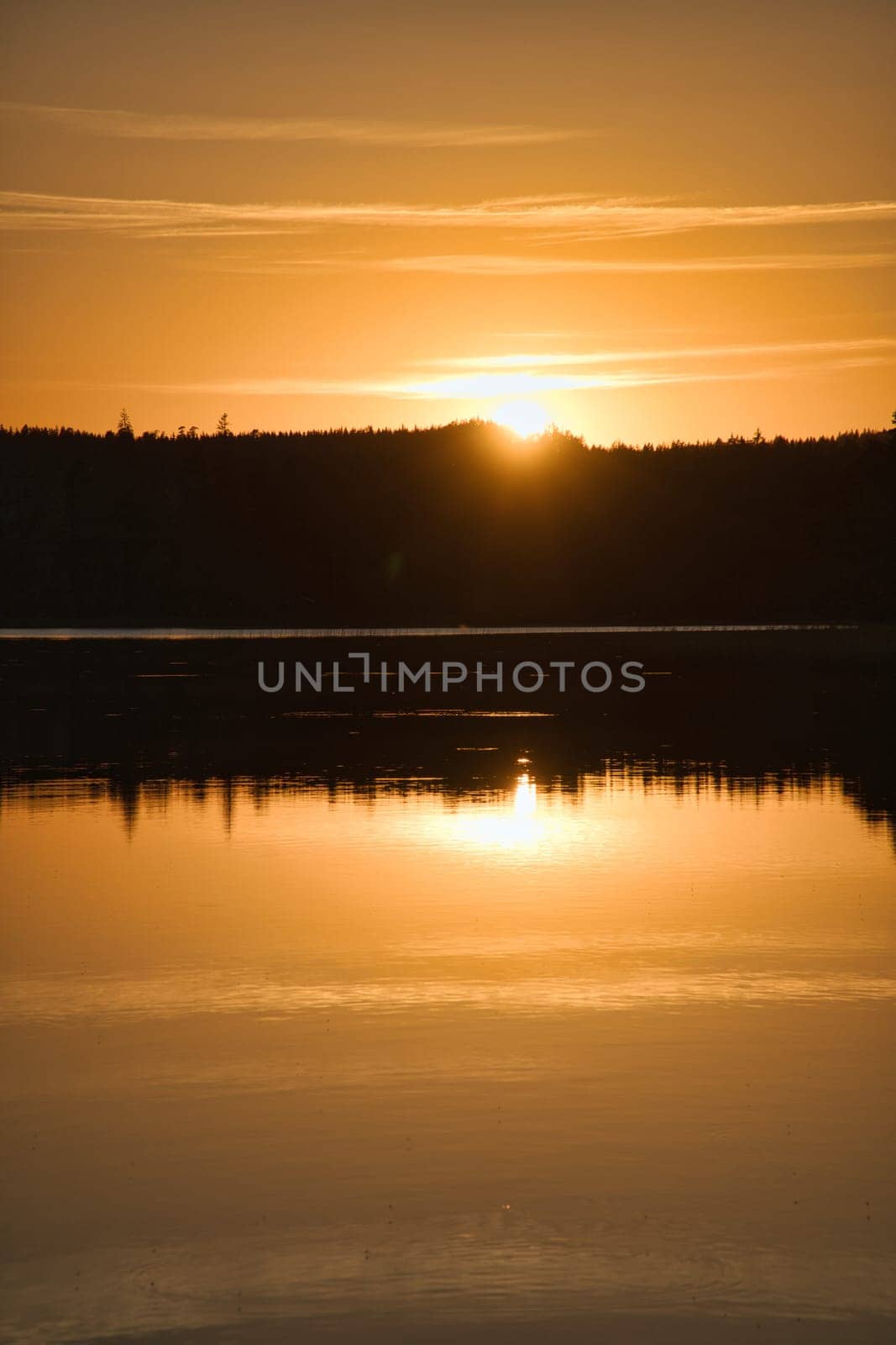 Sunset with reflection on a Swedish lake in Smalland. Romantic evening mood. Landscape shot from Scandinavia in nature