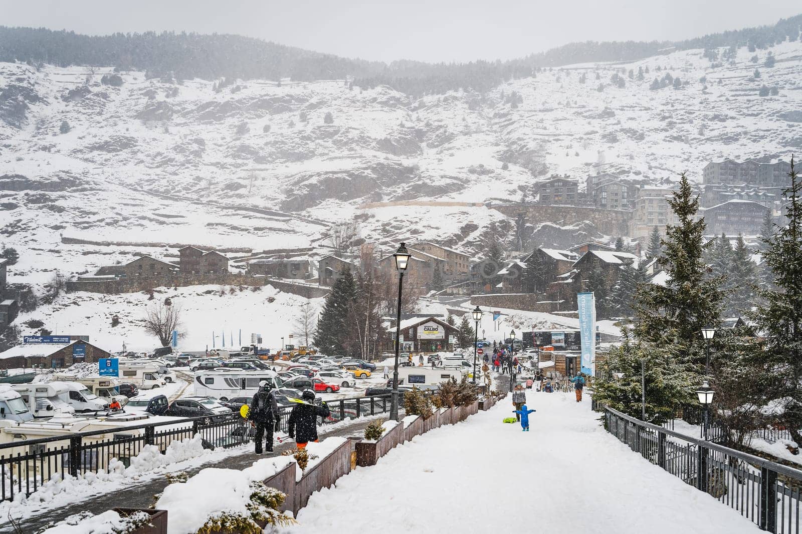 El Tarter, Andorra, Jan 2020 People, families with ski and snowboard equipment walking on main parking with ski lifts, Pyrenees Mountains