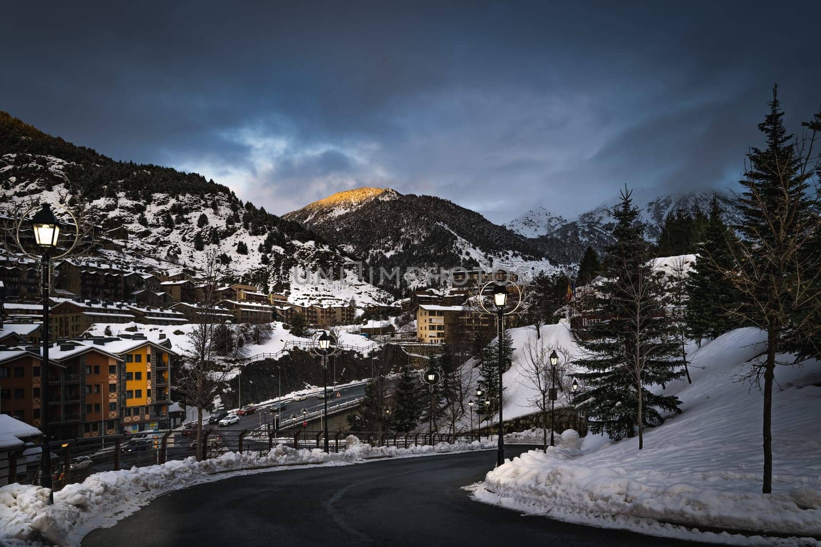 El Tarter village at dusk or night fall with lit street lamps and last sunlight illuminating mountain peak in Pyrenees mountains, Grandvalira, Andorra