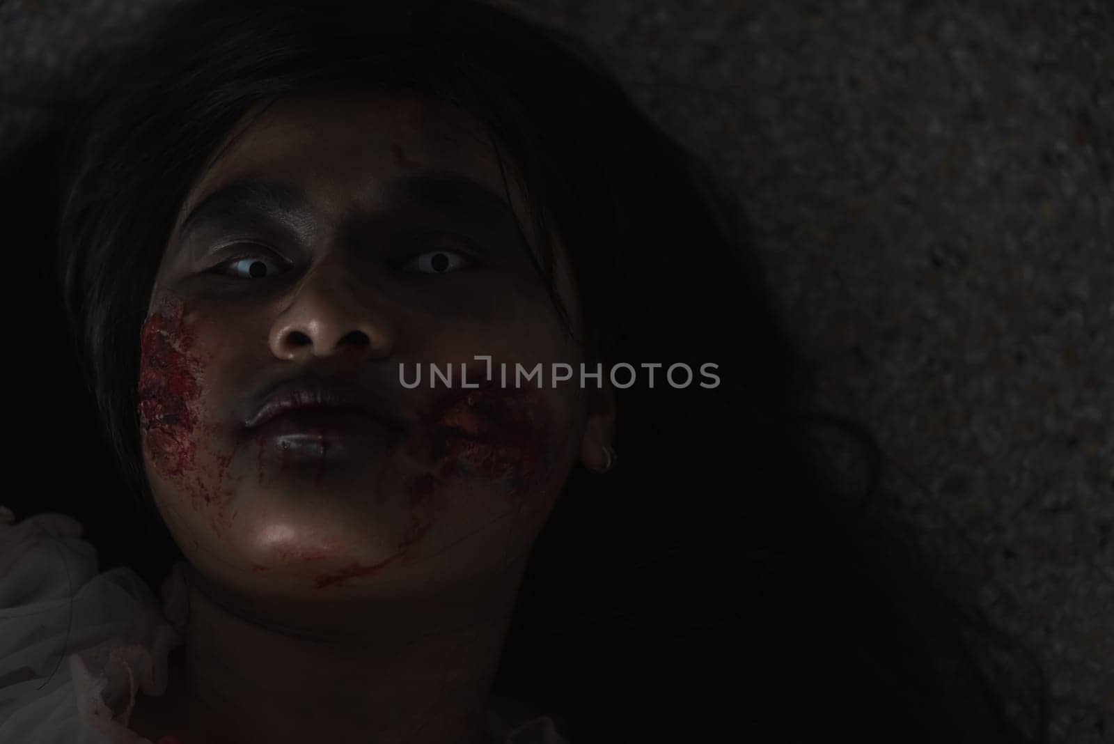 Horror evil woman ghost creepy lying dead in a dark room at house. Female zombie in blood devil is scary she haunted at the abandoned building, Happy Halloween festival day concept
