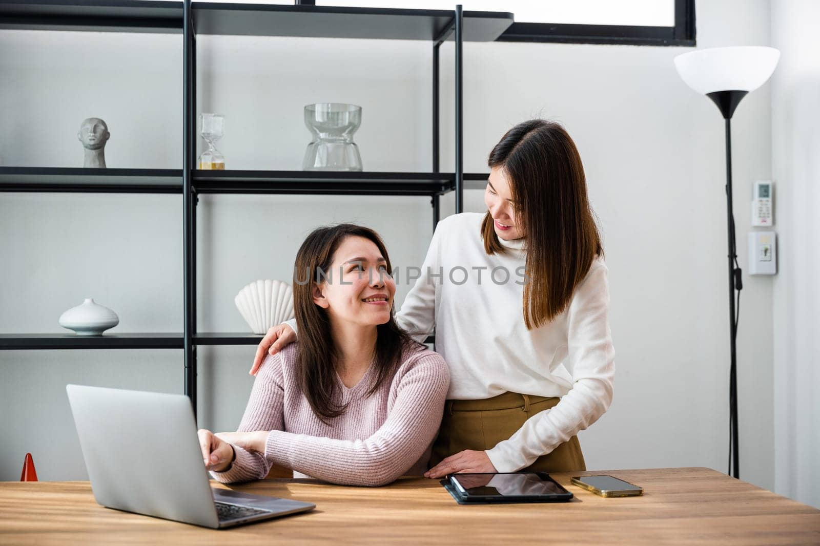 Asian middle age woman and teen they shoping online on computer, mother and teenage daughter looking at laptop computer at home office, happy family work together