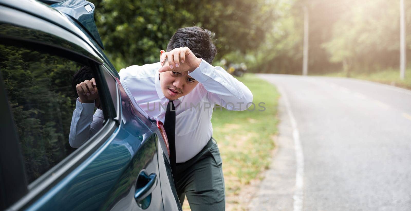 Asian businessman car broken has problems with car down during go to work in morning he pushing out of gas on road at countryside, business man have trouble roadside, problem transportation