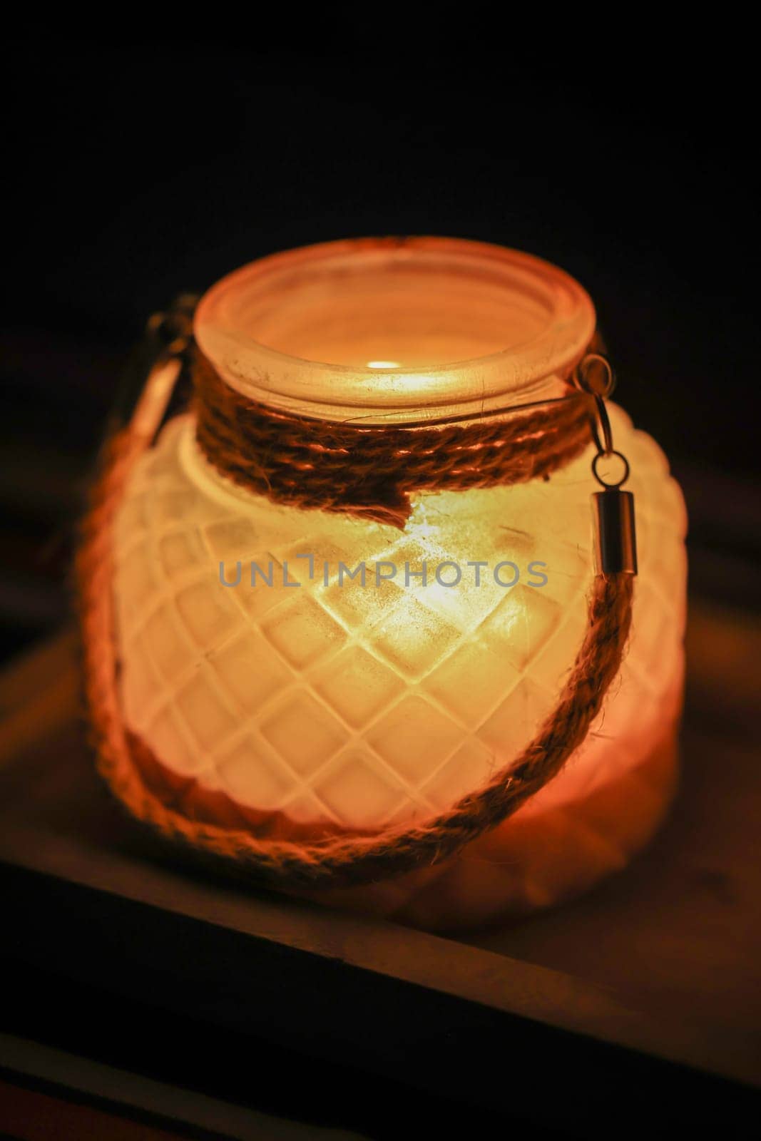 A lantern with a tea light atmospherically illuminates a table in the evening.
