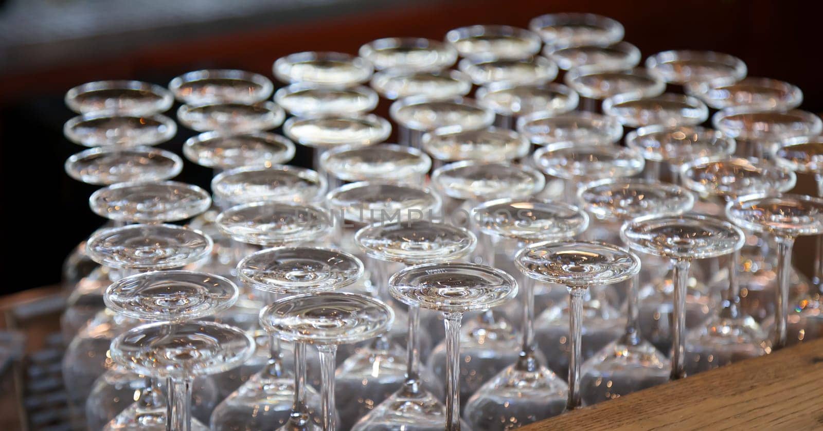 Many clean wine glasses are waiting at the counter to be filled.