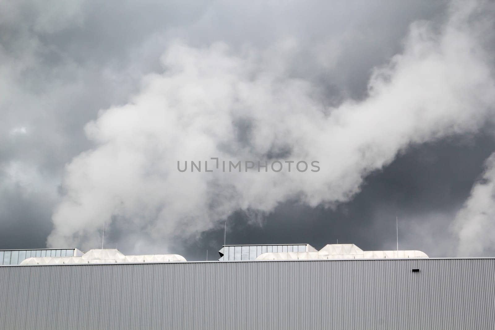 Dark clouds with water vapor over the building of a factory.