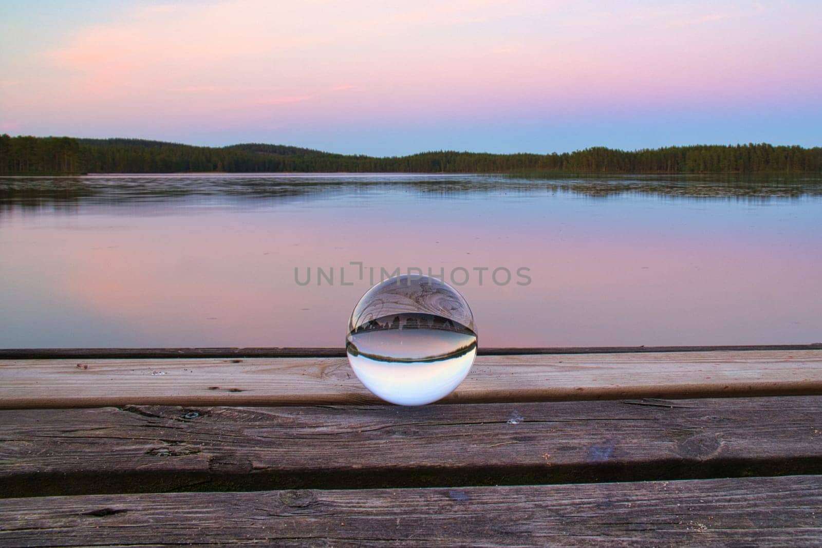Glass ball on a wooden pier at a Swedish lake at evening hour. Nature shot from Scandinavia