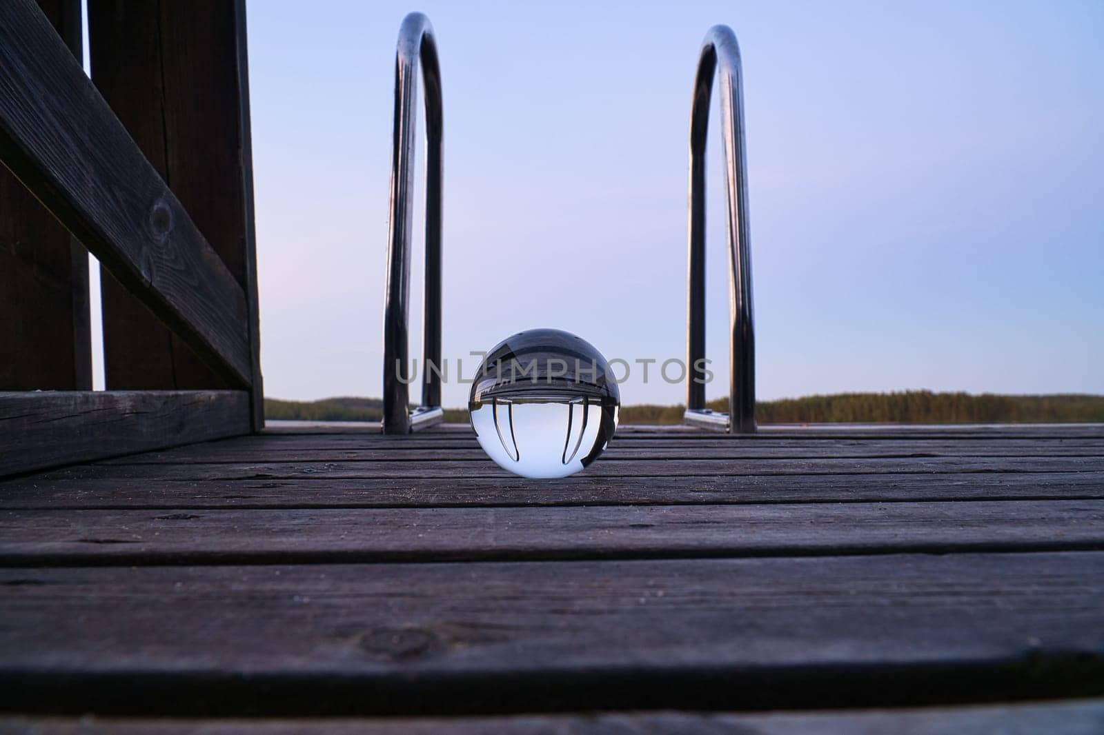 Glass ball on a wooden pier at a Swedish lake at evening hour. Nature shot from Scandinavia