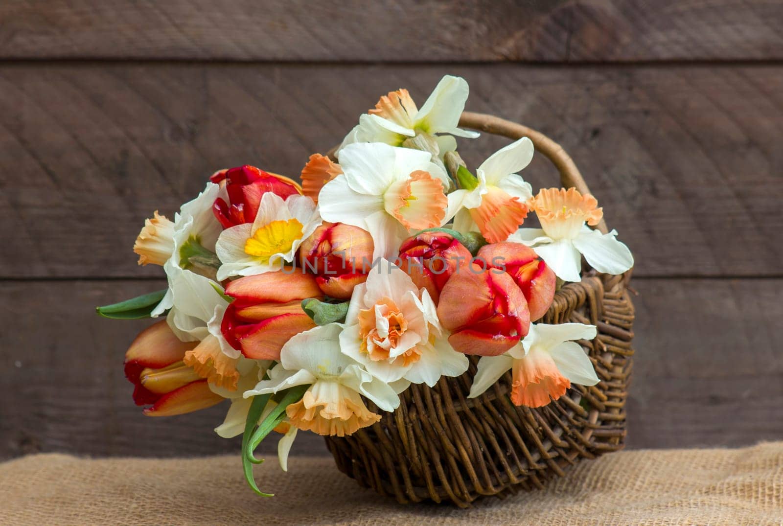 bouquet of spring flowers in a basket on wooden background