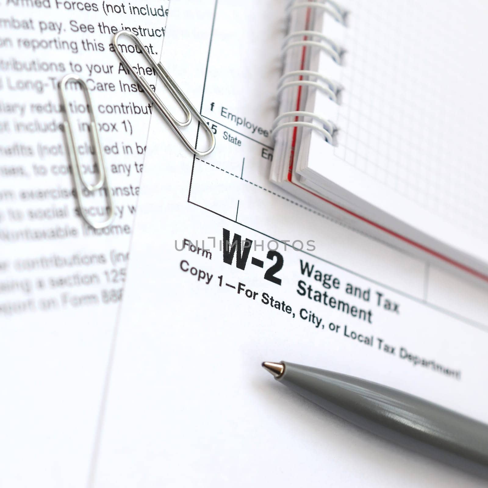 The pen and notebook on the tax form W-2 Wage and Tax Statement. The time to pay taxes