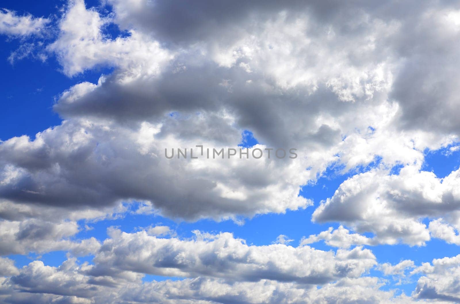 A blue sky with lots of white clouds of different sizes