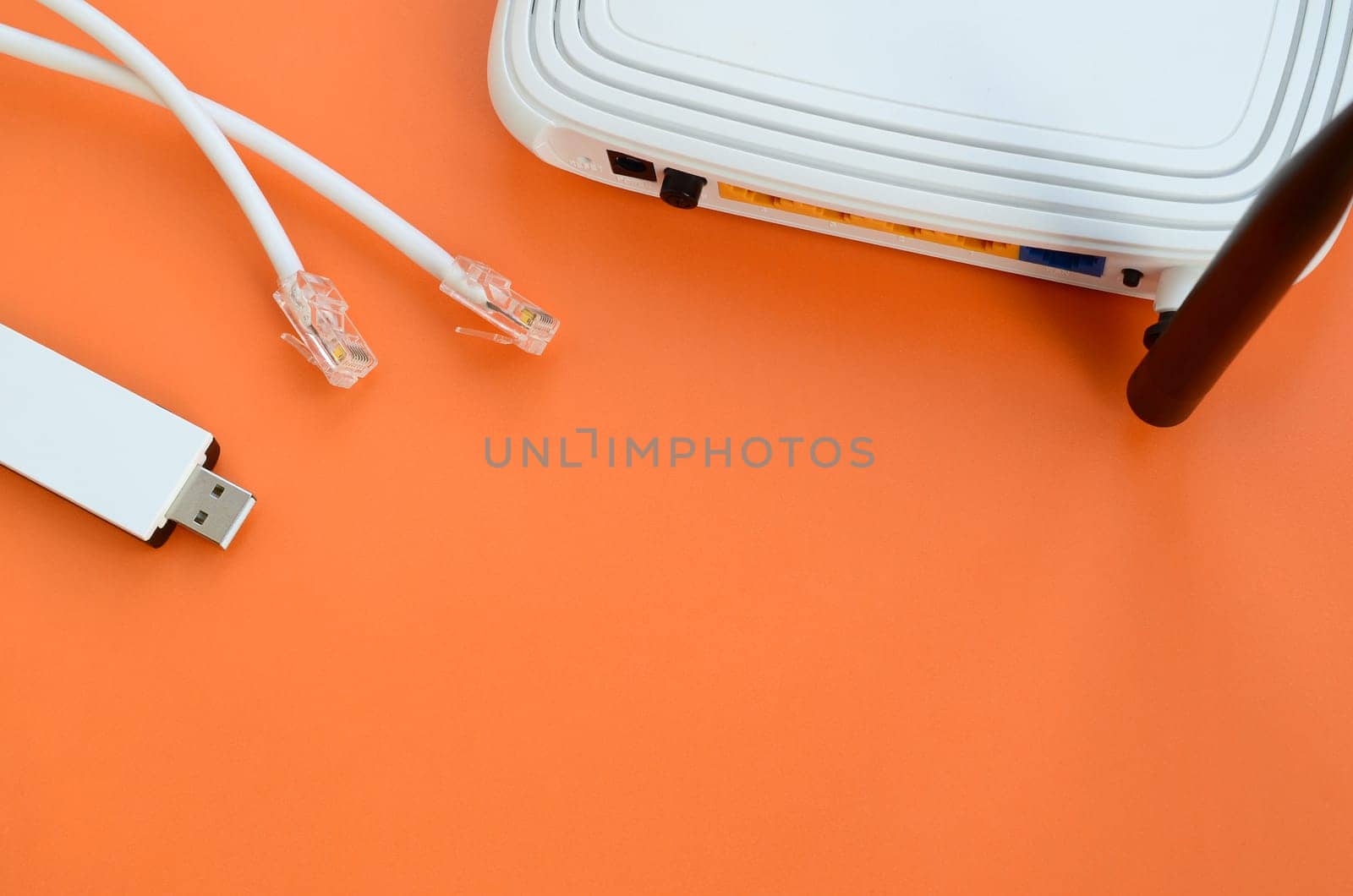 Internet router, portable USB wi-fi adapter and internet cable plugs lie on a bright orange background. Items required for internet connection