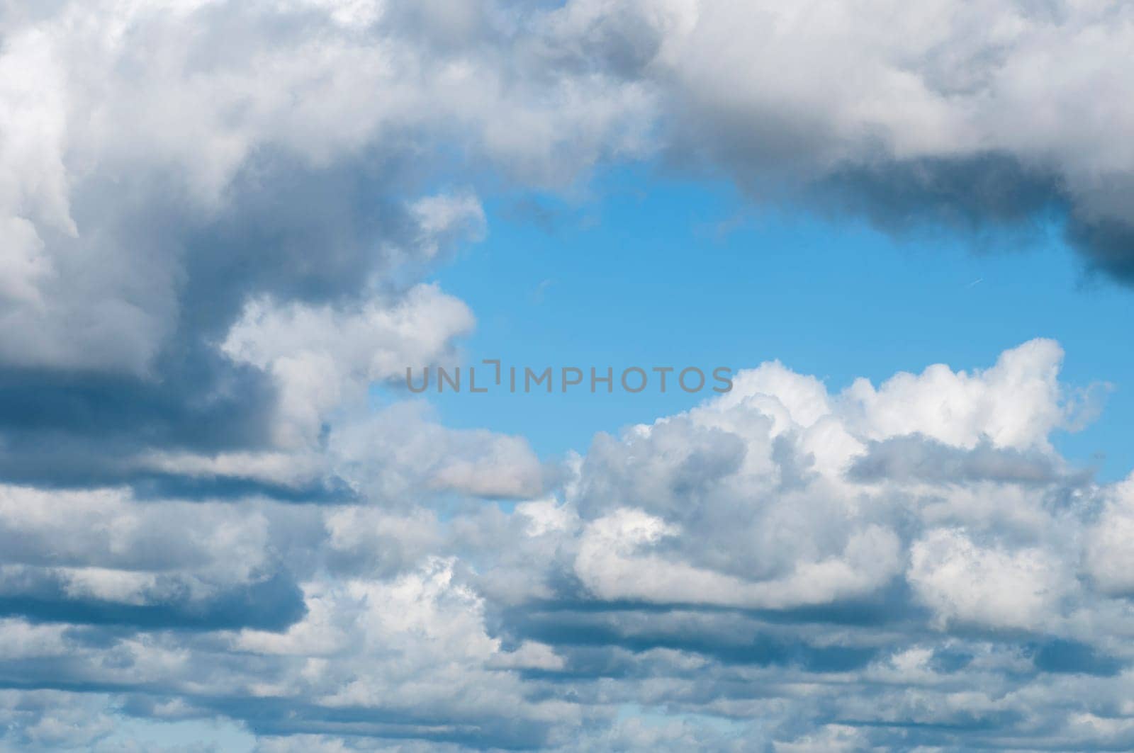 Full frame view of gathering clouds with clear blue sky in the middle.